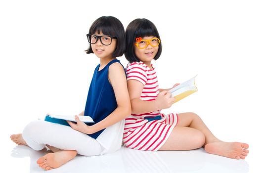 Asian girls wearing spectacles sitting on the floor with books