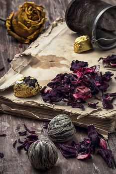 old book is strewn with the tea leaves on wooden background,tinted in vintage style