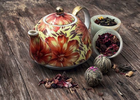 teapot and scattered tea leaves on vintage wooden background