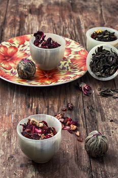 tea strainer and different varieties of tea leaves on wooden background.The toned image