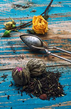 Tea leaves for brewing,tea spoon and dried yellow rose.The image is tinted in vintage style