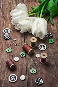 sewing accessories with a bouquet of fresh flowers.the image is tinted in vintage style