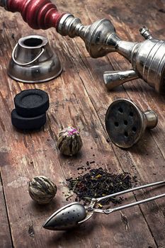 accessories to Smoking hookah and dry tea leaves.image is tinted in vintage style