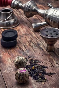 accessories to Smoking hookah and dry tea leaves.image is tinted in vintage style