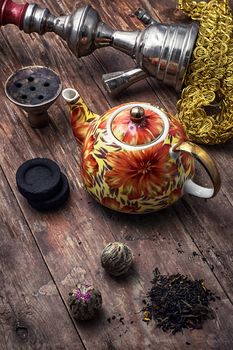 accessories to Smoking hookah and dry tea leaves.image is tinted in vintage style
