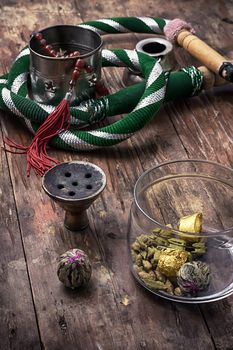 accessories to Smoking hookah and dry tea leaves.image is tinted in vintage style