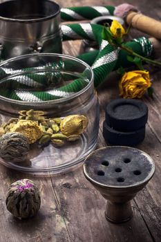 accessories to Smoking hookah and dry tea leaves.image is tinted in vintage style