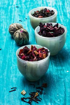 variety of dry tea leaves in jade stacks on turquoise wooden background.Toned image