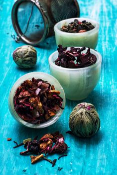 variety of dry tea leaves in jade stacks on turquoise wooden background.Toned image