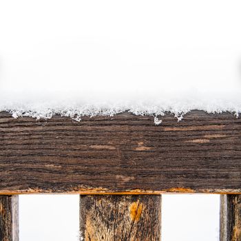 Detail of weathered painted wooden bench covered in snow, top of timber, plank or board with rungs or spokes, white copyspace on the top, winter time illustration or background