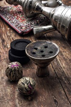 details hookah and dry elite tea leaves on wooden background.The toned image