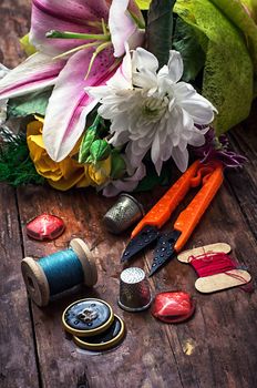 sewing accessories with a bouquet of fresh flowers.the image is tinted in vintage style