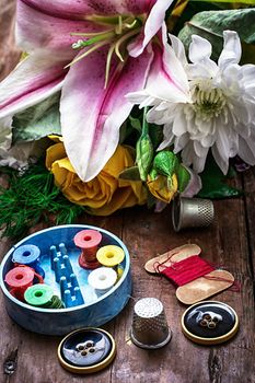 sewing accessories with a bouquet of fresh flowers.the image is tinted in vintage style