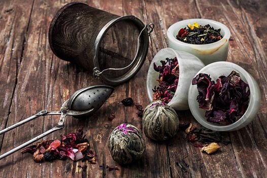 tea strainer and different varieties of tea leaves on wooden background.The toned image