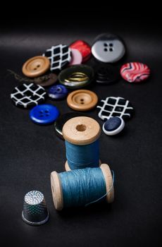 thread and buttons for sewing master on black background.Selective focus