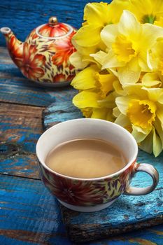 Cup of tea and a bunch of fresh daffodils.Selective focus