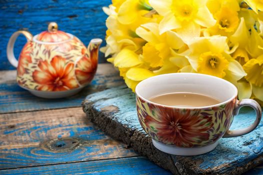 Cup of tea and a bunch of fresh daffodils.Selective focus