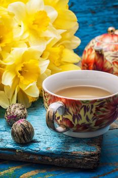 Cup of tea and a bunch of fresh daffodils.Selective focus