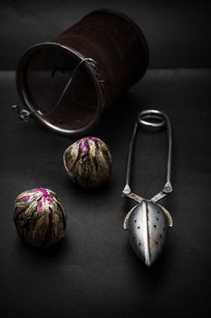 dry leaves of the tea infuser and accessories on black background