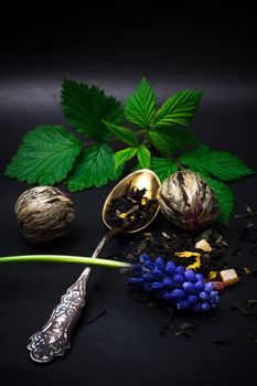 dry leaves of the tea infuser and accessories on black background