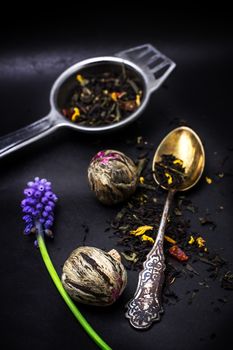 dry leaves of the tea infuser and accessories on black background