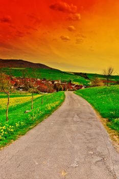 Asphalt Road Leading to the Small City in the Swiss Alps at Sunset