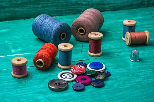 thread buttons for crafts on turquoise wooden background.Selective focus