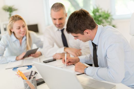 Business people having a meeting. Three business people looking at document and discussing in the office.