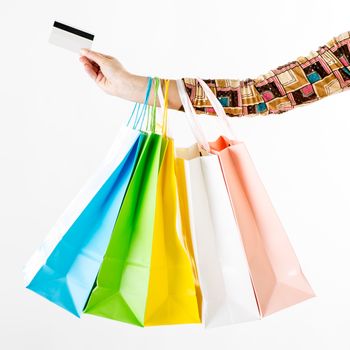 Close up of a woman hand with many shopping bags and credit card. White background.