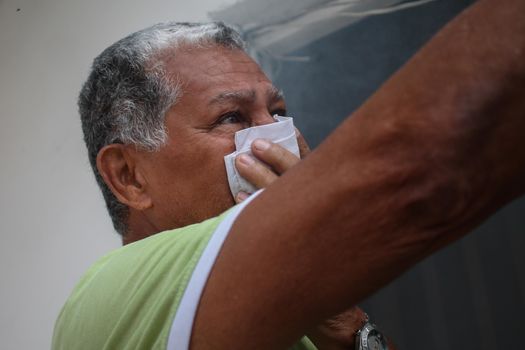 VENEZUELA, Caracas: A resident of Caracus, Venezuela protects himself from smoke as fumigation crews work to exterminate mosquitoes carrying the Zika virus in the slums of Caracas, Venezuela on February 3, 2016. As of February 4, there have been reports of at least 255 cases of the rare Guillain-Barre syndrome  which causes the immune system to attack the nerves  potentially linked to the Zika virus in Venezuela.