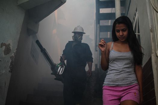 VENEZUELA, Caracas: A member of a fumigation crew waits for a girl to exit her home to allow for the extermination of Aedes mosquitoes carrying the Zika virus in the slums of Caracas, Venezuela on February 3, 2016. As of February 4, there have been reports of at least 255 cases of the rare Guillain-Barre syndrome  which causes the immune system to attack the nerves  potentially linked to the Zika virus in Venezuela.