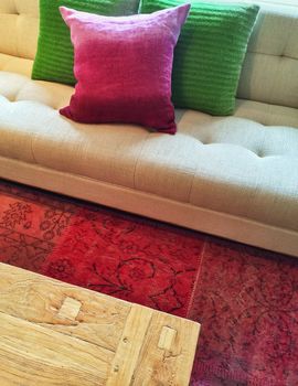 Beautiful interior with sofa, table, red rug, and bright cushions.