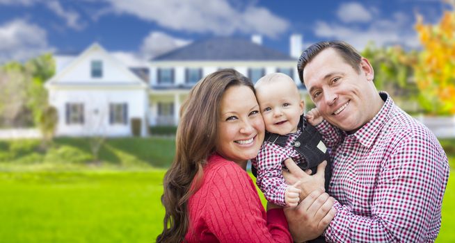 Happy Young Family With Baby Outdoors In Front of Beautiful Custom Home.
