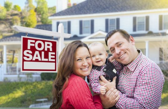 Happy Young Family In Front of For Sale Real Estate Sign and House.