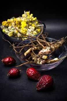 berries are dried rose hips and herbs on black background.Selective focus