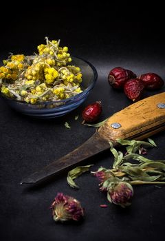 berries are dried rose hips and herbs on black background.Selective focus