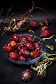 berries are dried rose hips and herbs on black background