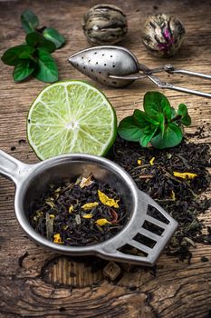 scattered on wooden table tea leaves and tea strainer.Selective focus