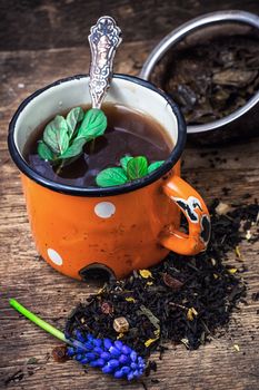 enamel cup with herbal tea amid scattered on the welding table