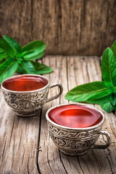 two iron bowls with herbal tea on background of mint leaves.Selective focus