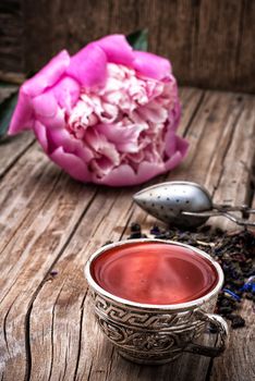 iron bowls with herbal tea on the background of the peony bud and scattered welding elite tea.Selective focus.Photo tinted