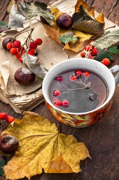 Cup with tea and fallen autumn leaves on wooden table.Selective focus