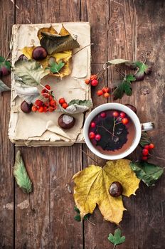 Cup with tea and fallen autumn leaves on wooden table.Selective focus