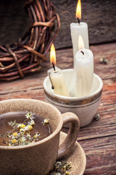 fragrant chamomile tea and burning candles in rustic style.Selective focus