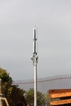 Cell phone tower against an overcast sky with rusting steel in the foreground.