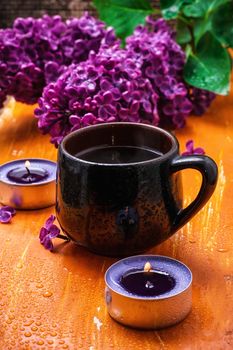 fragrant spring flower tea on the background of burning candles and lilac bouquet