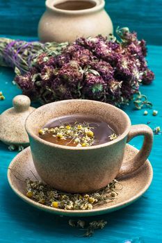 ceramic cup with tea brewed from dried chamomile and medicinal herbs.Selective focus