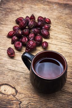 black cup medicinal tea on the background of scattered dried rose hips