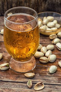 beer light beer on wooden table with saucer of salted pistachios.Photo tinted