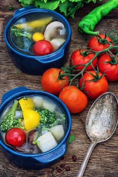 traditional soup of fresh vegetables in blue pot on wooden background.Photo tinted